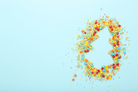 Colorful sprinkles in a shape of fir tree on blue background