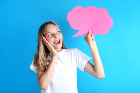 Young girl holding speech bubble on blue backgroundの写真素材