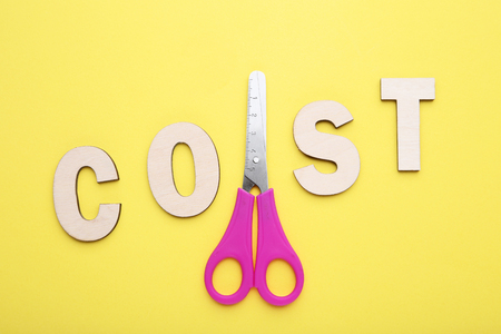 Word Cost and scissors on yellow backgroundの写真素材