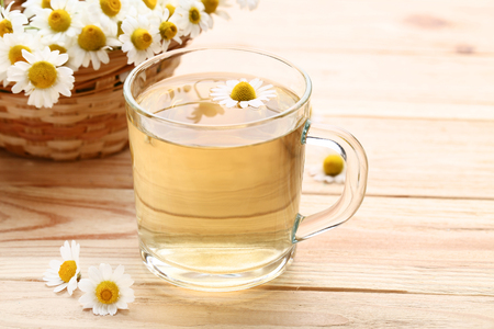 Cup of tea with chamomile flowers on brown wooden tableの写真素材