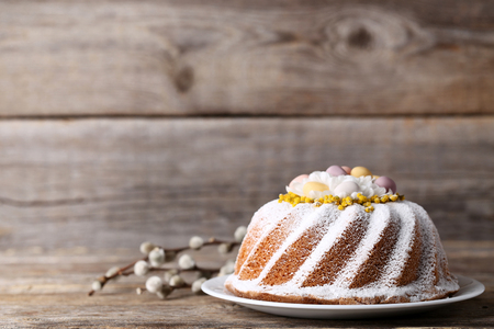 Easter cake in plate with tree branches on grey wooden table