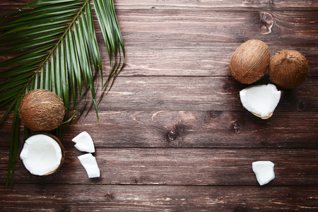 Ripe coconuts with palm leafs on brown wooden tableの写真素材