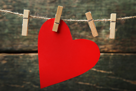 Red paper heart hanging on rope on wooden backgroundの写真素材