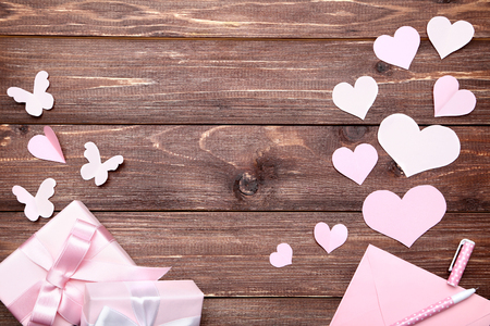 Paper hearts with gift box and envelope on brown wooden tableの写真素材