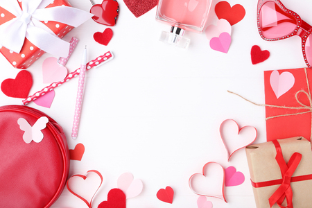 Paper hearts with gift boxes, perfume bottle and pens on white backgroundの写真素材