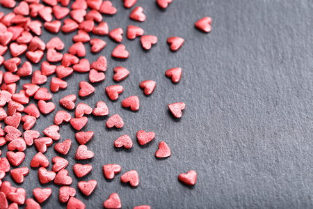 Red heart shaped sprinkles on black backgroundの写真素材