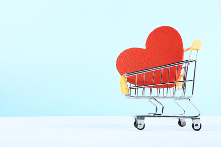 Shopping cart with red heart on wooden tableの写真素材