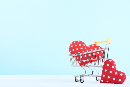 Shopping cart with red fabric hearts on blue backgroundの写真素材
