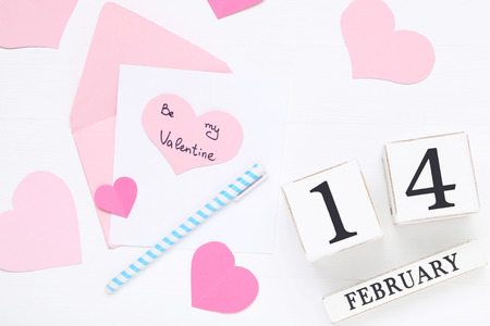 Inscription Be My Valentine with paper hearts and wooden calendar on white backgroundの写真素材