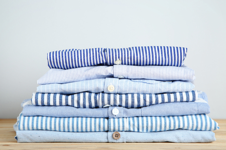 Stack of folded shirts on grey backgroundの写真素材