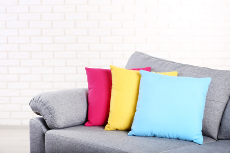 Modern grey sofa with colorful pillows on brick wall backgroundの写真素材
