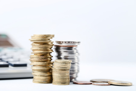 Stack of coins with calculator on the table