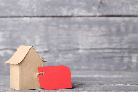 Paper house with sale tag on grey wooden tableの写真素材