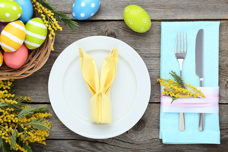 Kitchen cutlery with easter eggs and mimosa flowers on wooden tableの写真素材