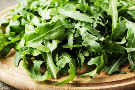 Green arugula leafs on wooden cutting boardの写真素材