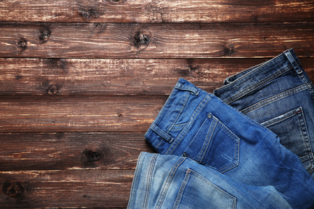 Folded jeans on brown wooden tableの写真素材