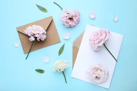 Eustoma flowers with envelope and sheet of paper on blue backgroundの写真素材