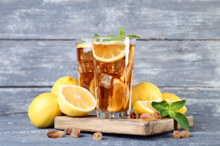 Ice tea in glasses with lemon and mint leafs on wooden tableの写真素材