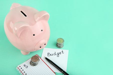 Pink piggy bank with coins and notepad on mint backgroundの写真素材