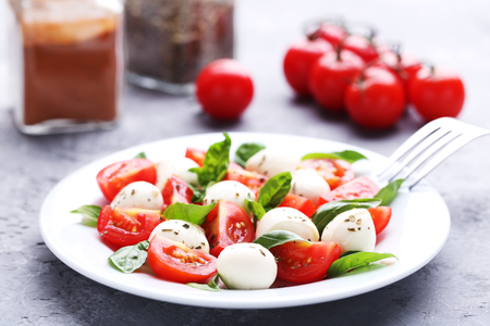 Mozzarella, tomatoes and basil leafs on grey wooden tableの写真素材