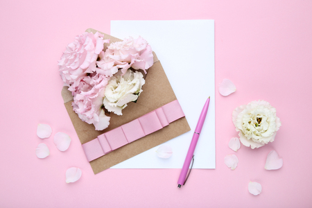 Eustoma flowers with envelope and sheet of paper on pink backgroundの写真素材