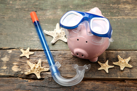 Pink piggy bank with diving mask and snorkel on wooden tableの写真素材