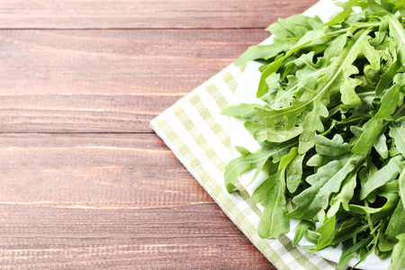 Green arugula leafs in plate with napkin on wooden tableの写真素材