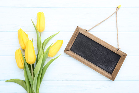 Bouquet of yellow tulips with blank frame on wooden tableの写真素材
