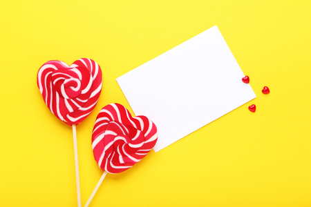 Heart shaped lollipops and greeting card on yellow backgroundの写真素材