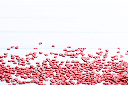 Red heart shaped sprinkles on wooden tableの写真素材