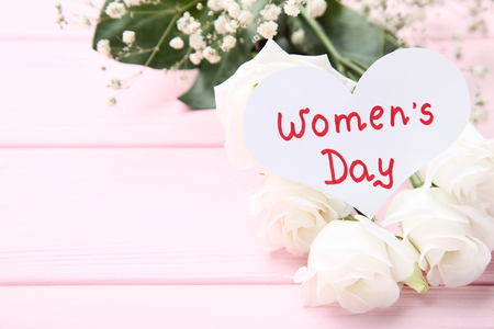 Text Women's Day with eustoma and gypsophila flowers on pink wooden tableの写真素材