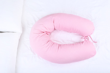 Pink body pillow on white bedの写真素材