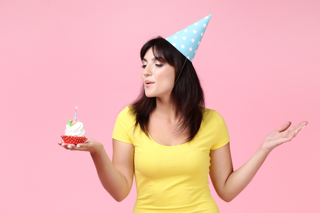Young woman with birthday cupcake on pink backgroundの写真素材