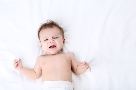 Cute baby lying on white bed