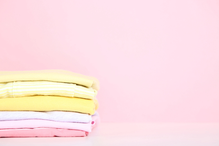 Stack of folded clothes on pink backgroundの写真素材