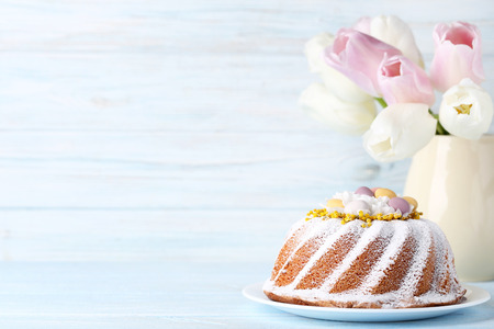 Easter cake with tulip flowers in vase on wooden table