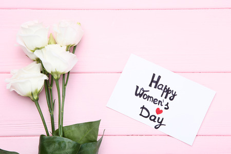 Text Happy Women's Day with eustoma flowers on pink wooden tableの写真素材