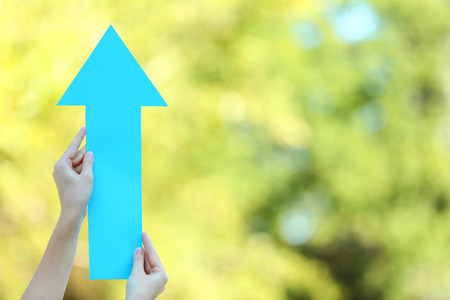 Female hands holding blue paper arrow on the street