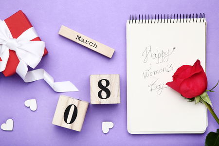 Wooden calendar with red rose, gift box and text Happy Women's Dayの写真素材