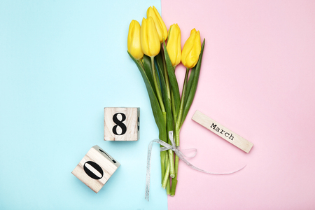 Women's Day on wooden calendar with yellow tulips on colorful backgroundの写真素材