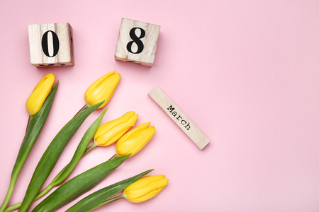Women's Day on wooden calendar with yellow tulips on pink backgroundの写真素材