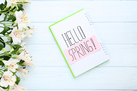 Alstroemeria flowers and notepad with text Hello Spring on wooden tableの写真素材