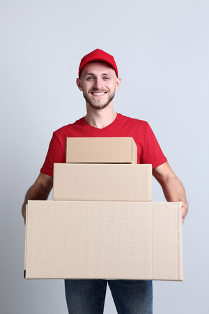 Delivery man with cardboard boxes on grey backgroundの写真素材