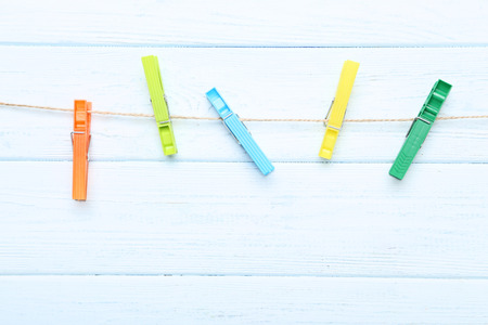Colorful clothespins hanging on wooden background