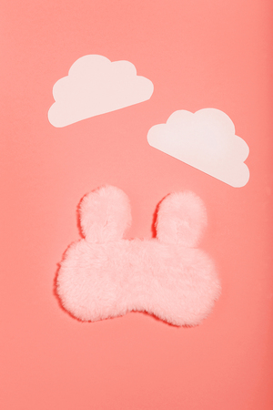 Sleeping mask with paper clouds on living coral color background. Minimalism conceptの写真素材