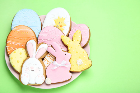 Easter gingerbread cookies in plate on green background