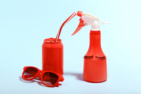 Aluminum can with sunglasses and spray bottle on blue background. Minimalism conceptの写真素材