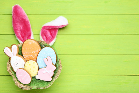 Easter gingerbread cookies in basket with rabbit ears on wooden table