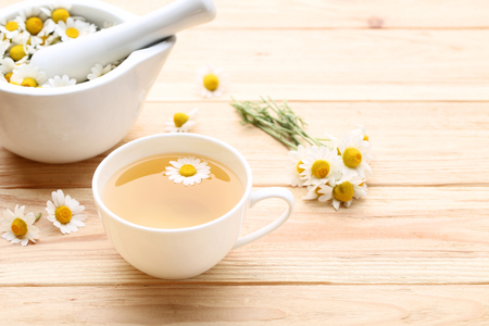 Cup of tea with chamomile flowers on brown wooden tableの写真素材