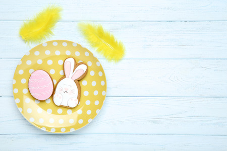 Easter gingerbread cookies in plate with yellow feathers on wooden tableの写真素材